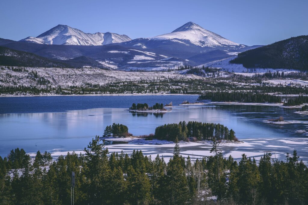 Winter lake and snow-covered pines at Keystone with towering mountains under clear blue sky wallpaper