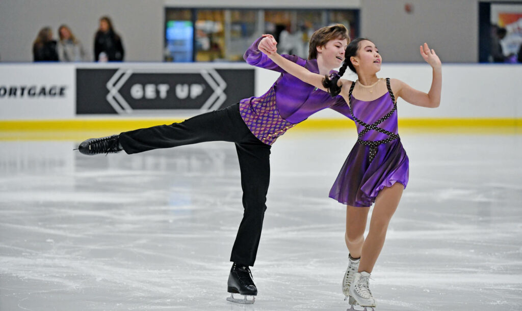 Kiana Pan and llya Mondrowski performing synchronized figure skating in purple costumes on ice Wallpaper