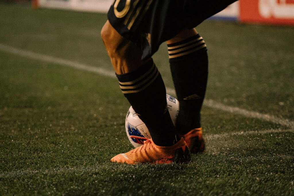 Close-up of footballer in orange cleats controlling soccer ball on turf high-quality sports wallpaper