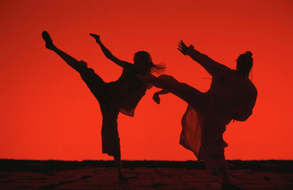 Dynamic silhouettes of two fighters in action Kill Bill scene red background wallpaper