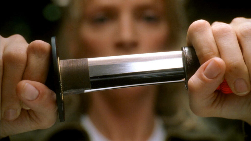 Close-up of shiny katana unsheathing Kill Bill wallpaper reflecting intense dramatic style