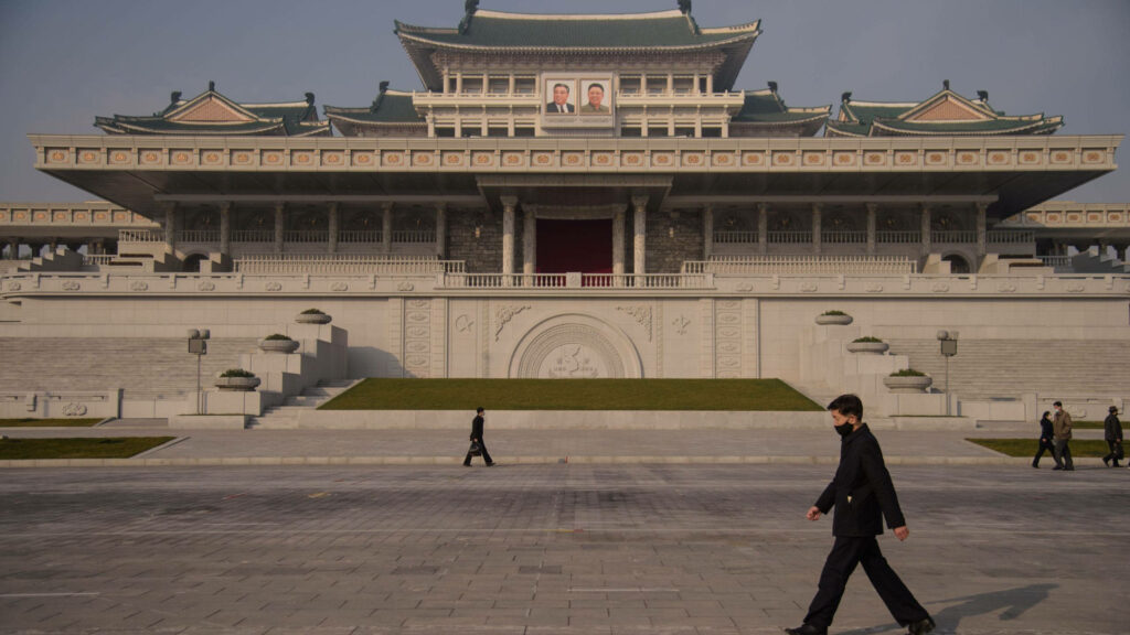 Traditional grand building with portraits at Kim Il Sung Square Pyongyang under hazy sky Wallpaper