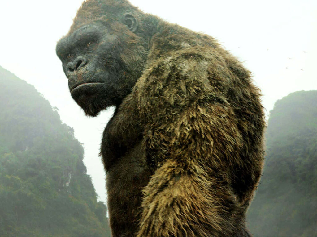 King Kong towering over misty cityscape with rugged mountains urban skyline wallpaper background
