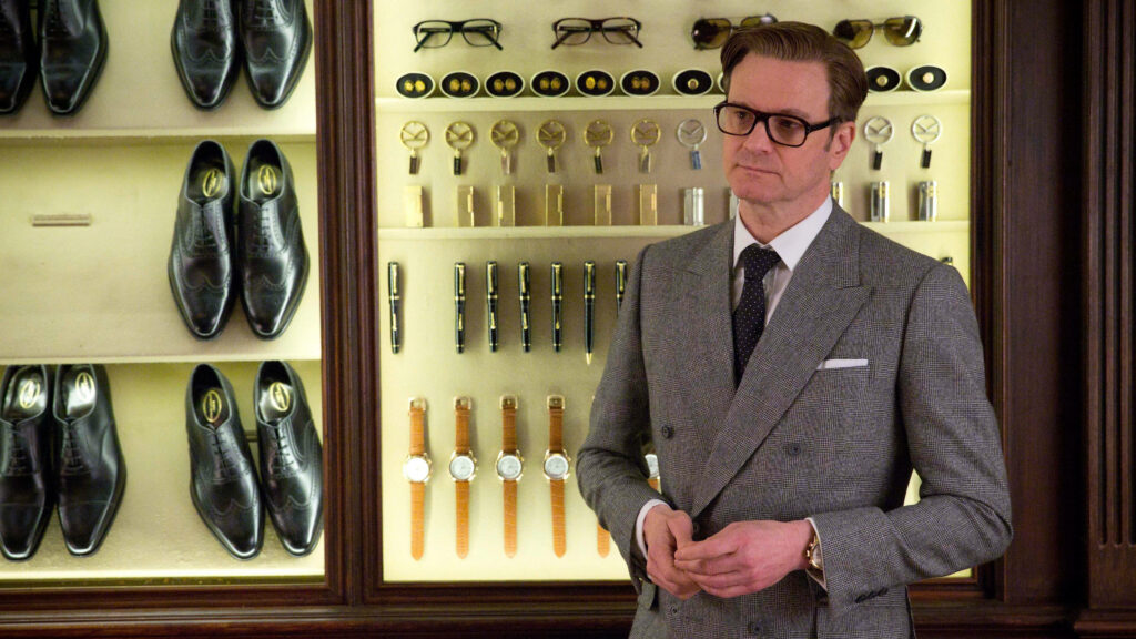 Kingsman agent poses before luxury display of secret weapons disguised as stylish accessories Wallpaper
