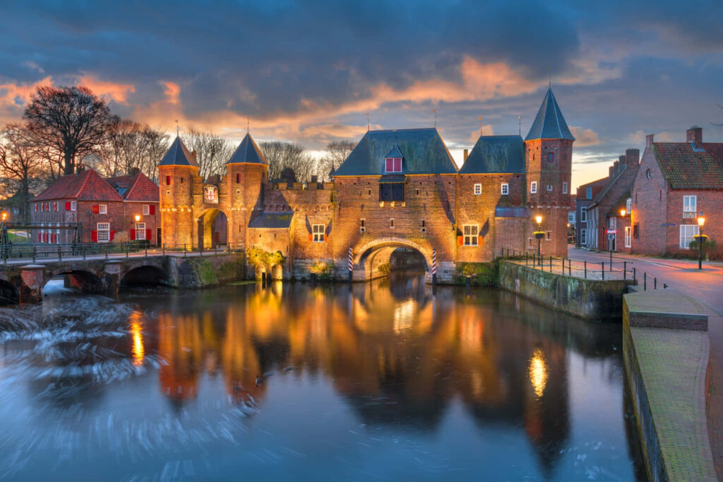 Koppelpoort medieval gate in Amersfoort illuminated at twilight reflected in calm water wallpaper