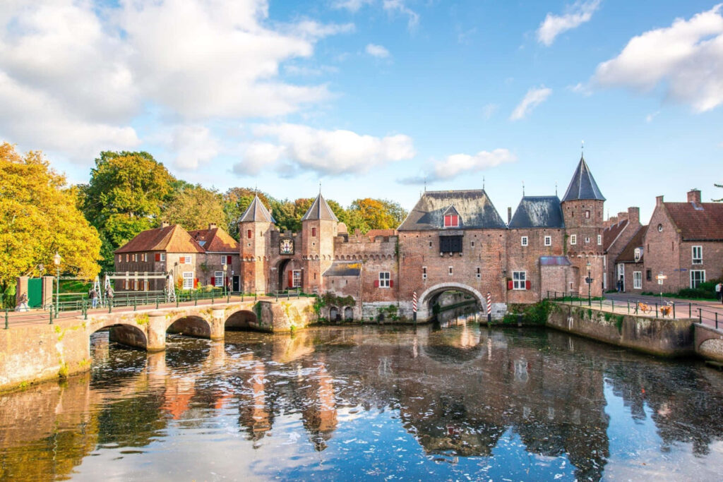 Koppelpoort medieval gate in Amersfoort reflected in calm water with autumn trees and blue sky Wallpaper