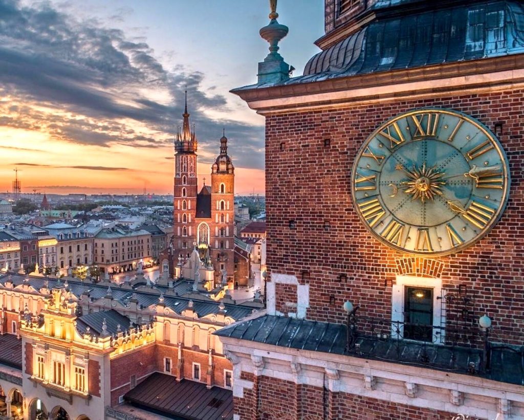 Kraków Rynek Główny sunset view with Town Hall Tower clock and St Mary’s Basilica in golden light Wallpaper