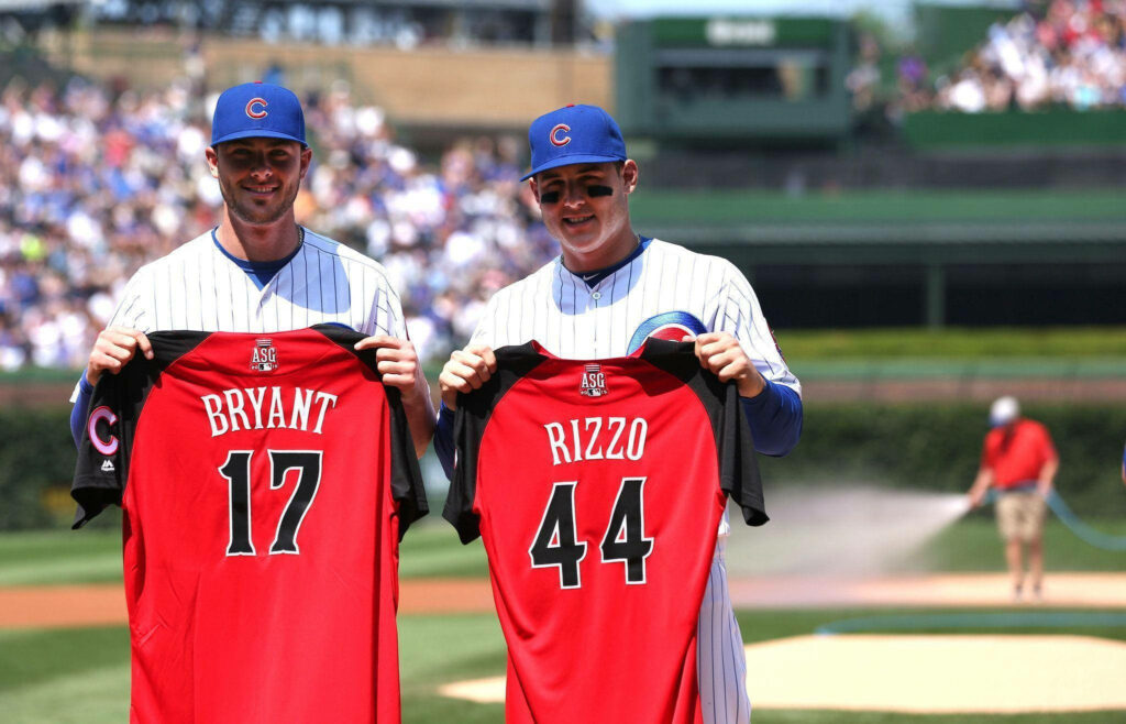 Kris Bryant and Anthony Rizzo in Cubs pinstripe uniforms holding red All-Star jerseys at Wrigley Field Wallpaper