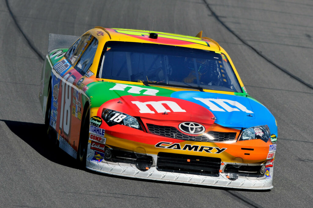 Kyle Busch M&M's Toyota Camry NASCAR race car number 18 speeding on track vibrant design Wallpaper