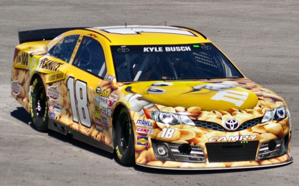 Kyle Busch yellow 18 NASCAR M&M's race car speeding on track professional stock car racing wallpaper