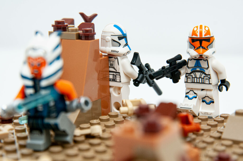 LEGO Clone Troopers in white blue and orange armor march with blasters on desert battlefield wallpaper