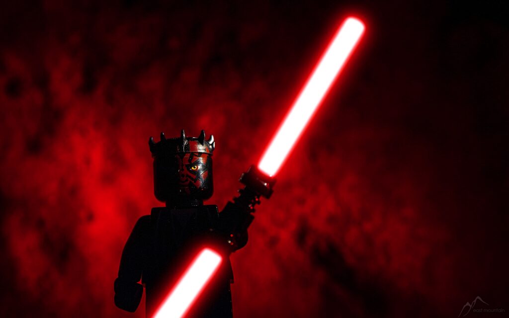 LEGO Darth Maul with double-bladed red lightsaber on fiery red Star Wars wallpaper background