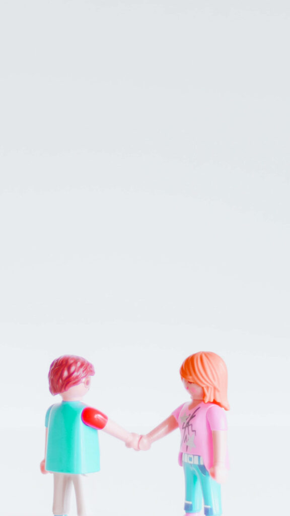Two LEGO toys shaking hands on white background symbolizing friendship and teamwork Wallpaper