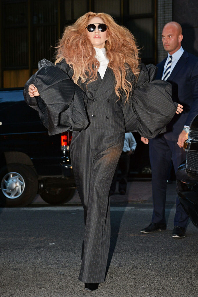 Lady Gaga wearing dramatic Comme Des Garçons pinstripe suit with oversized ruffled sleeves confident style Wallpaper