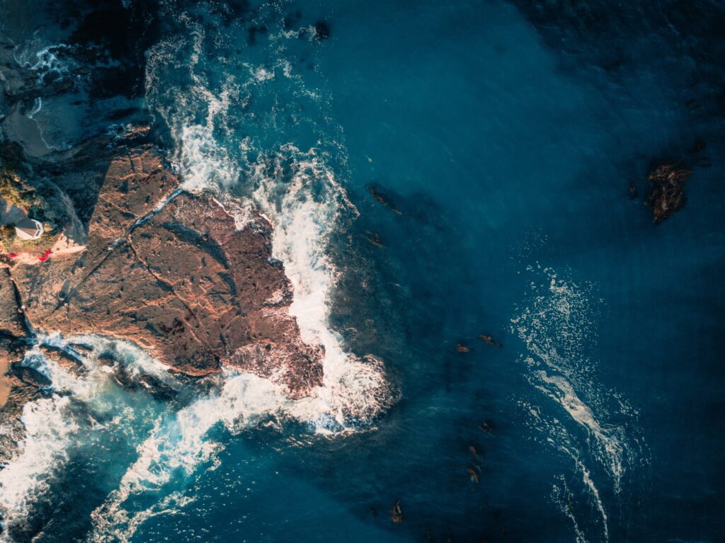 Top view of Laguna Beach with powerful waves crashing on rugged rocks vibrant ocean scenery Wallpaper