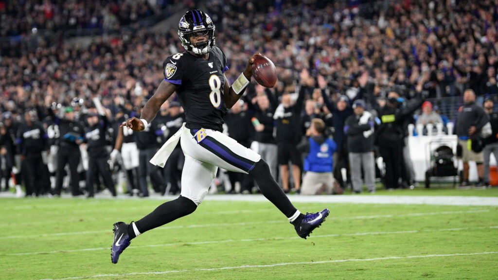 Lamar Jackson mid-air in Baltimore Ravens uniform electrifying football action wallpaper background