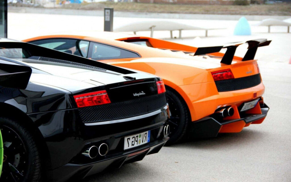 Two Lamborghini sports cars black and orange showing stylish rear designs and powerful presence Wallpaper