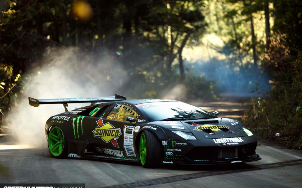 Lamborghini Murcielago racing decals drifting fast on sunlit forest road with smoke clouds wallpaper