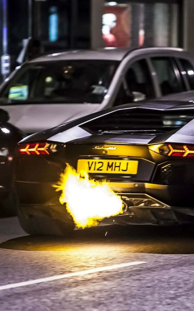 Lamborghini sports car speeding at night with flames shooting from exhaust dynamic wallpaper