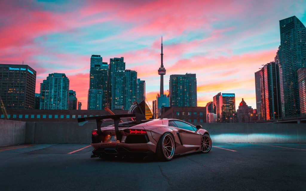 Lamborghini on rooftop with Toronto skyline and CN Tower at vibrant pink and blue sunset Wallpaper