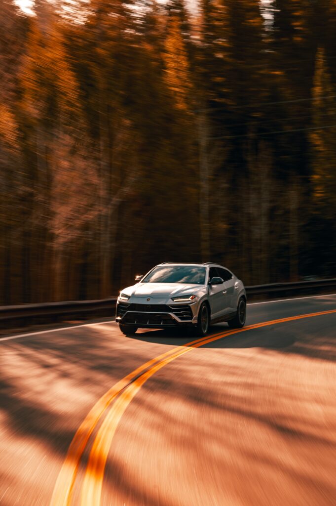 Vibrant Lamborghini Urus Driving Through Autumn Colors - Dynamic Wallpaper