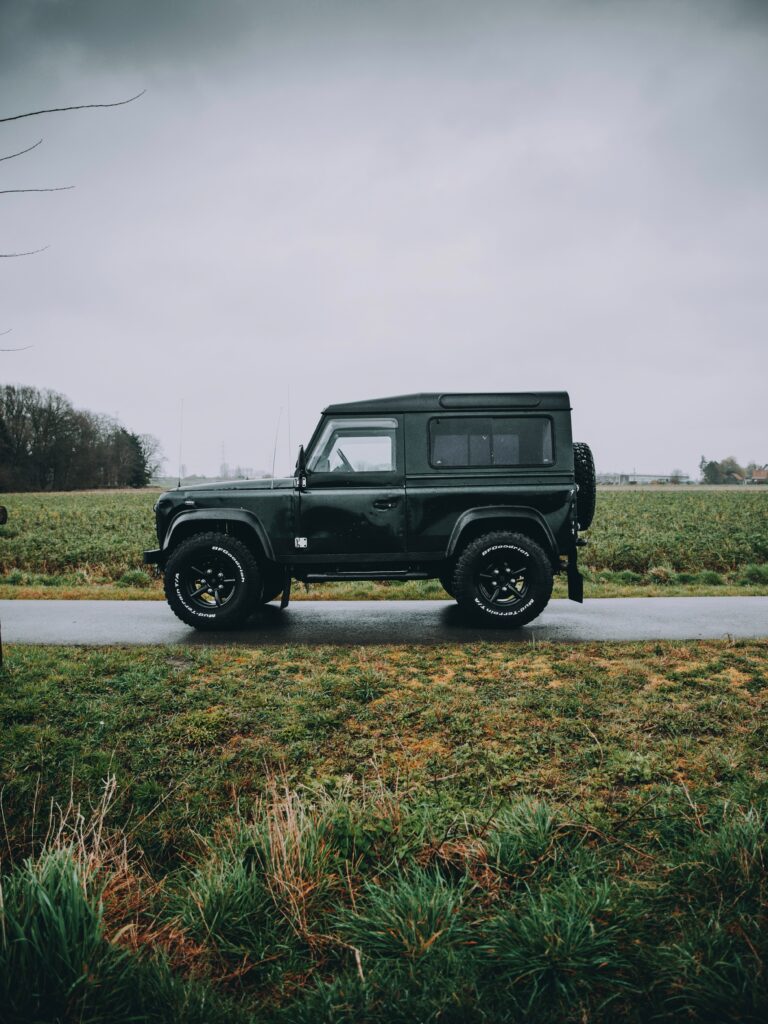 Rugged Land Rover SUV on Rural Road: Lush Green Background Wallpaper