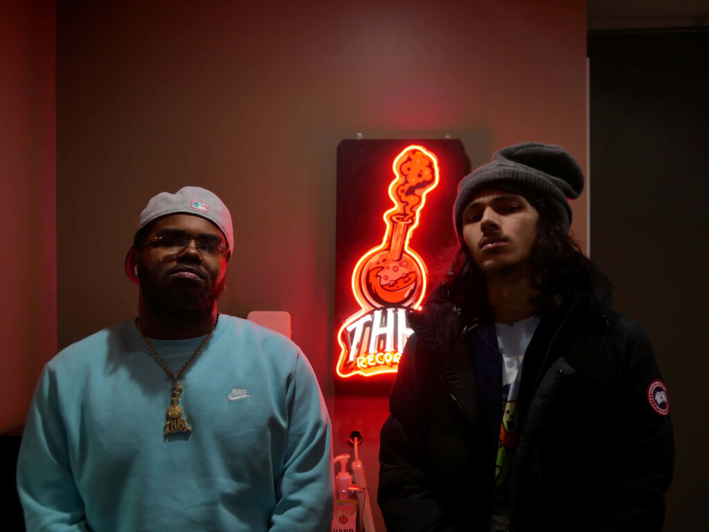 Lando Merriweather and BabyTron pose candidly by neon THIC Records sign American rappers wallpaper
