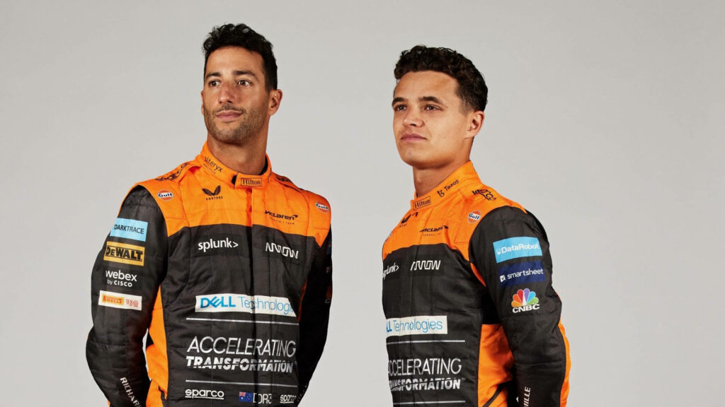 F1 drivers Lando Norris and Daniel Ricciardo in McLaren racing suits showing team spirit wallpaper