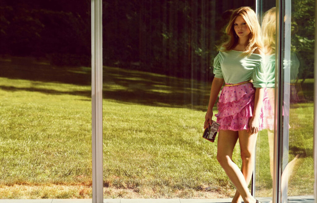 Lea Seydoux by sunlit window with serene green landscape stylish wallpaper background