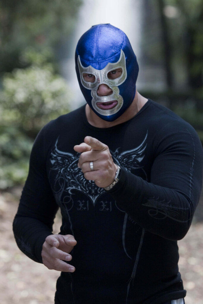 Masked luchador in blue silver mask exuding strength in forest background Lucha Libre wallpaper