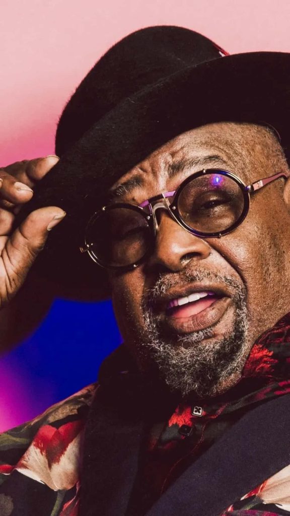 George Clinton portrait tipping fedora with round glasses on blue magenta gradient funk wallpaper