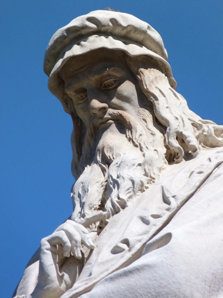 Detailed white Leonardo Da Vinci sculpture against clear blue sky Renaissance art wallpaper background
