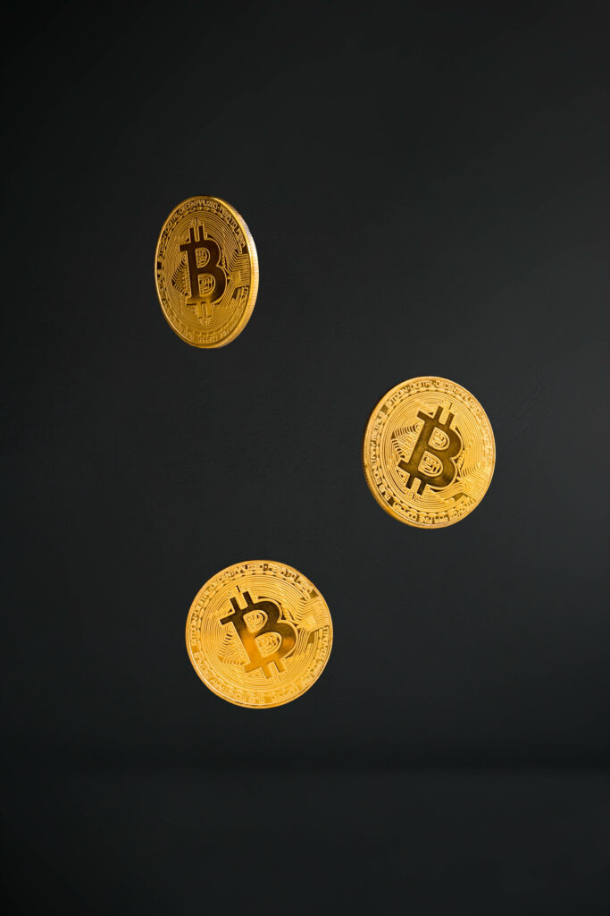 Three gold Bitcoin coins levitating on dark background modern cryptocurrency wallpaper design