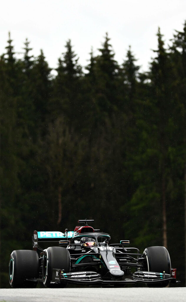 Lewis Hamilton driving Mercedes F1 car on forest track showcasing intensity and elegance racing Wallpaper