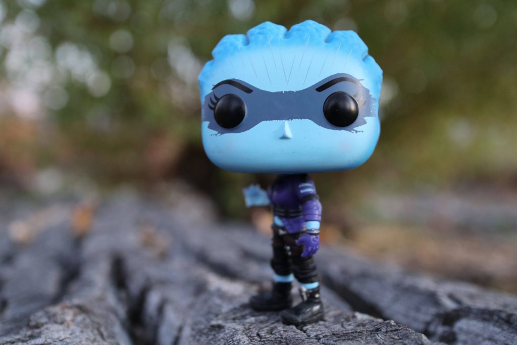 Macro photo of Liara T'Soni Funko Pop on bark with blurred green nature background wallpaper