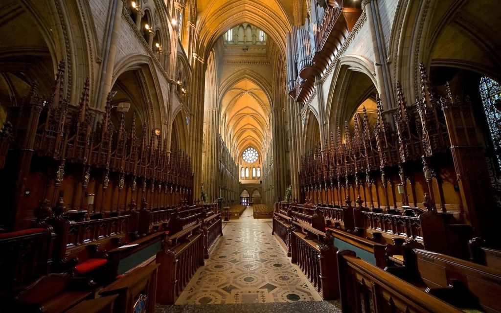 Interior view of Lichfield Cathedral with wooden choir stalls stone vaulting and rose window Wallpaper
