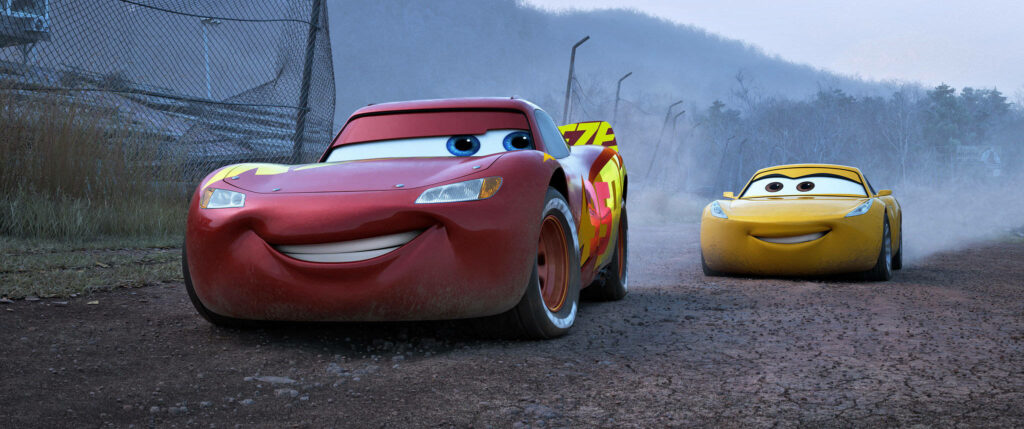 Lightning McQueen and Cruz Ramirez racing on dusty track with misty mountains in Cars 3 wallpaper