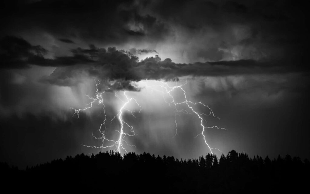 Stunning B&W Wallpaper of Lightning Over Silhouetted Forest