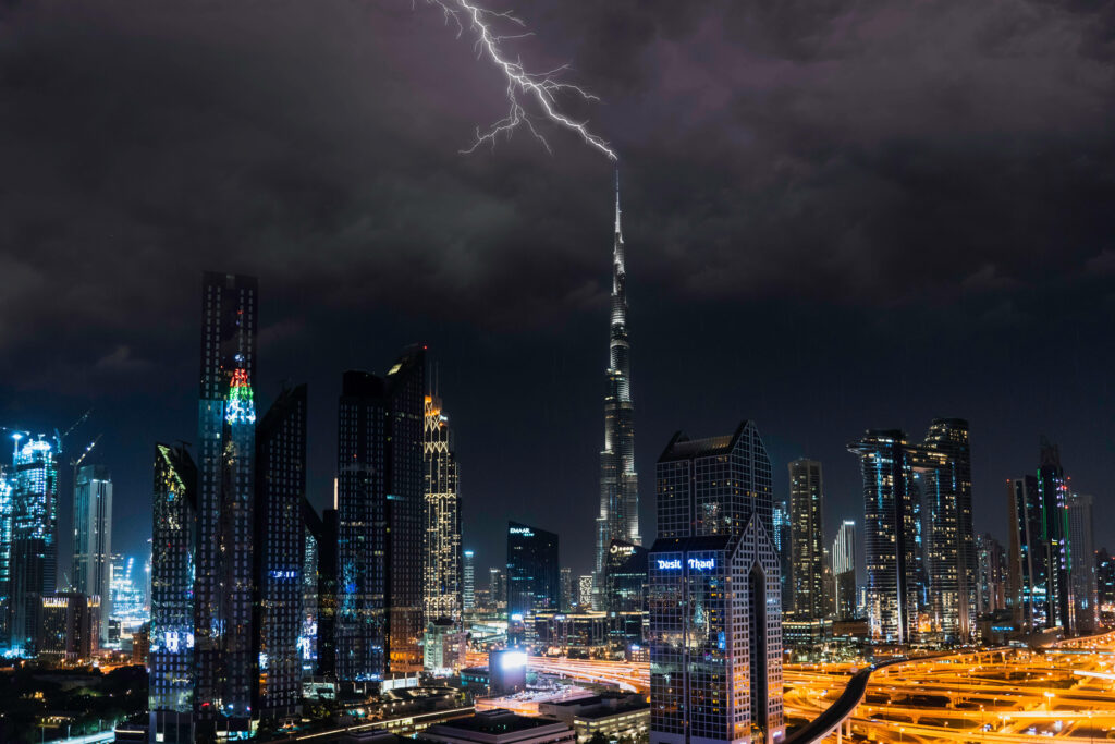 Lightning strikes Burj Khalifa at night with Dubai skyline illuminated under stormy clouds Wallpaper