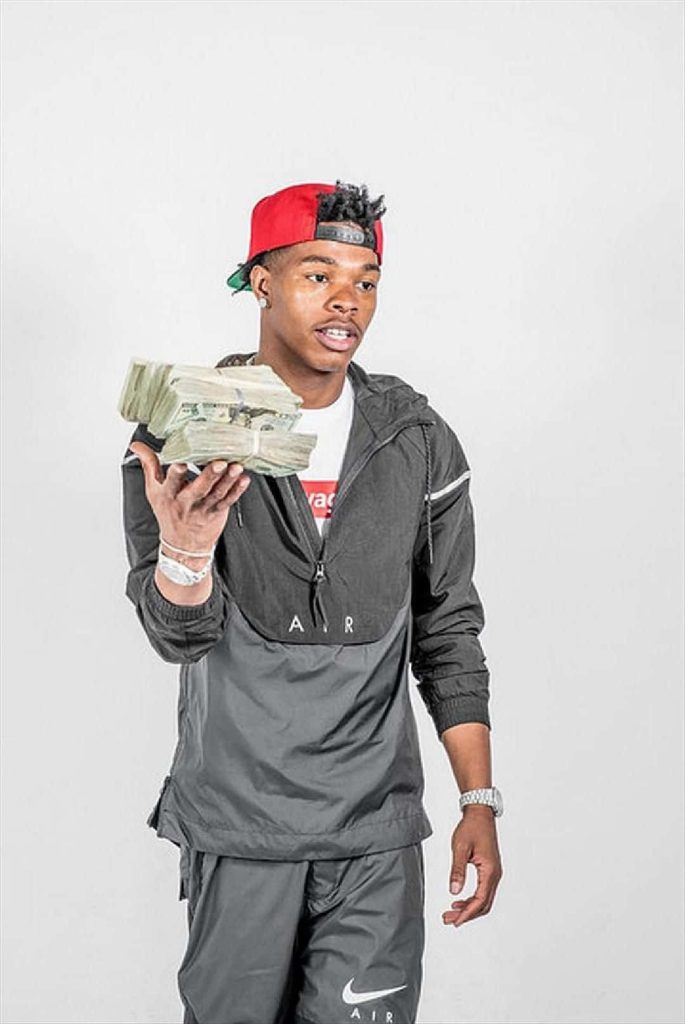 Rapper Lil Baby in red cap black Nike Air windbreaker holding cash studio portrait urban style Wallpaper