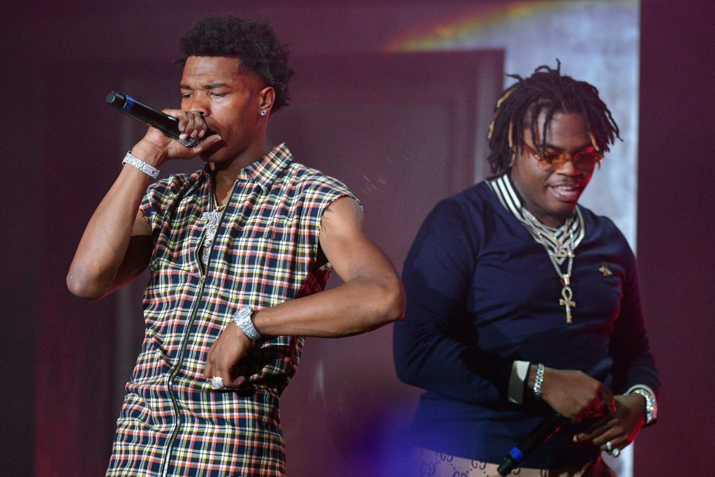 Lil Baby and Gunna performing live hip-hop concert in red stage lighting with stylish outfits Wallpaper