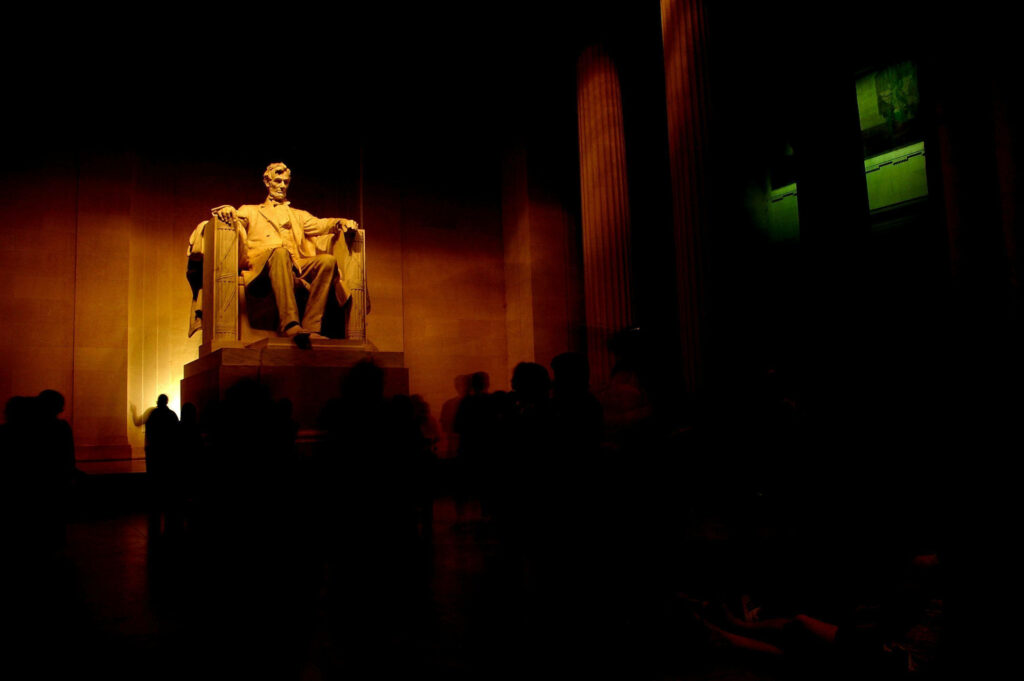Marble statue of Abraham Lincoln seated inside Lincoln Memorial with dramatic lighting background Wallpaper