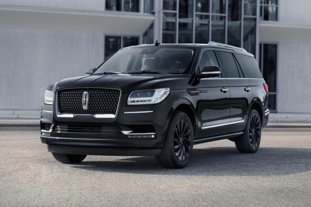 Lincoln Navigator SUV parked by modern building showcasing luxury design and bold presence background Wallpaper