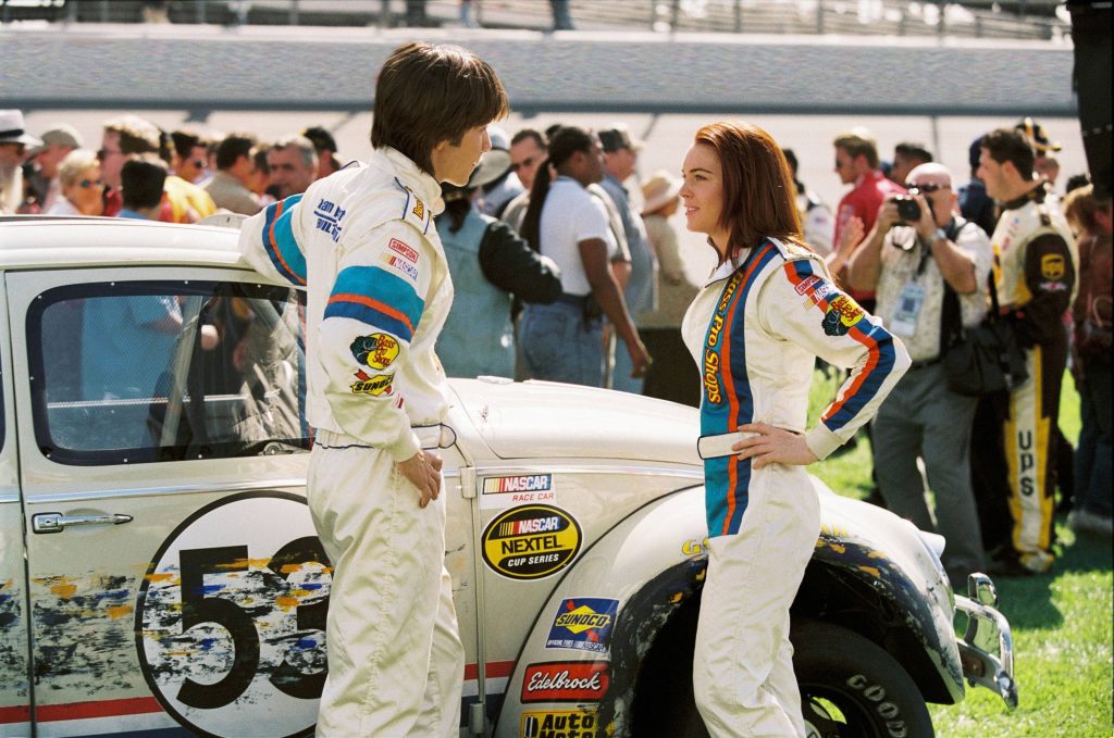 Lindsay Lohan and Justin Long in racing suits next to Herbie the Love Bug classic car wallpaper