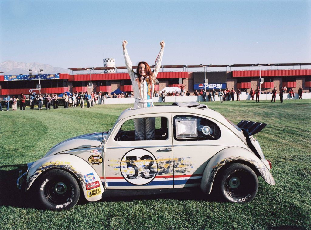 Lindsay Lohan in white racing suit celebrates victory standing through Herbie Fully Loaded Beetle sunroof Wallpaper