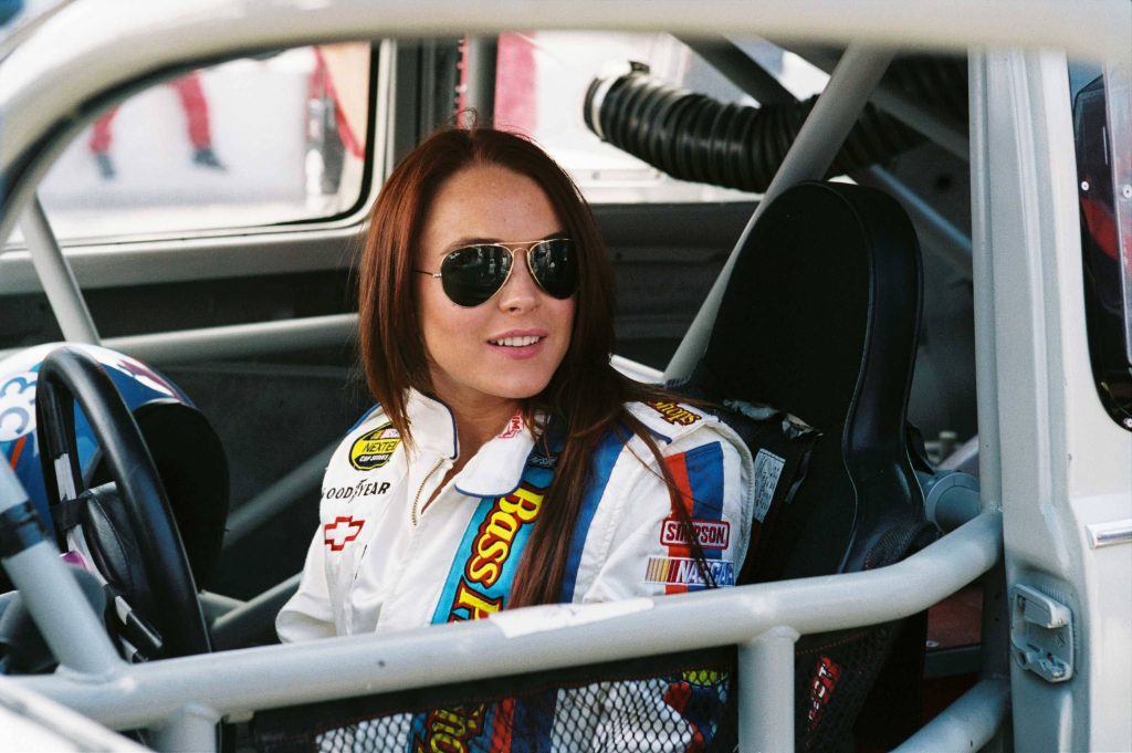 Lindsay Lohan in white NASCAR suit and aviator sunglasses driving Herbie Fully Loaded race car Wallpaper