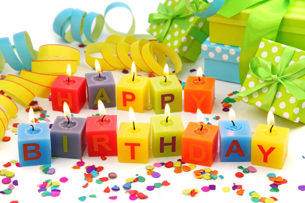 Festive birthday wallpaper with colorful lit cube candles spelling HAPPY BIRTHDAY confetti gifts ribbons