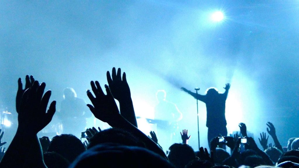 Blue-toned concert wallpaper fans silhouetted reaching performer with arms outstretched vibrant music