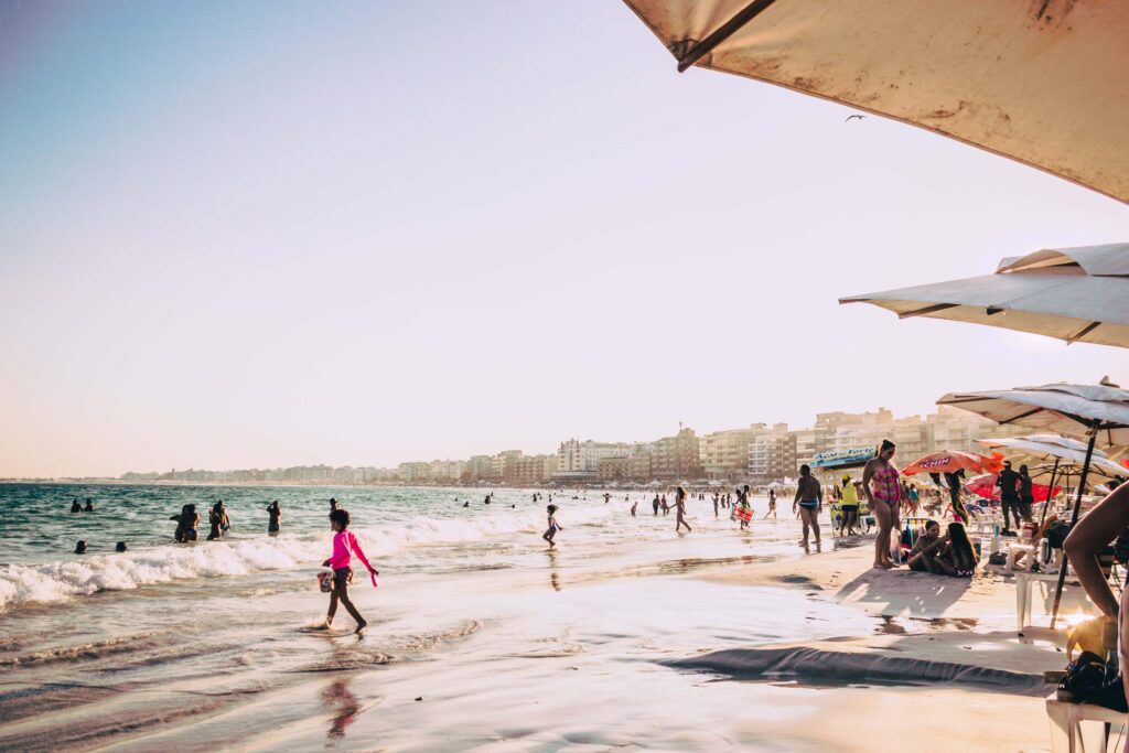 Vibrant Beach Scene with Sunbathers and Umbrellas by the Shore Wallpaper