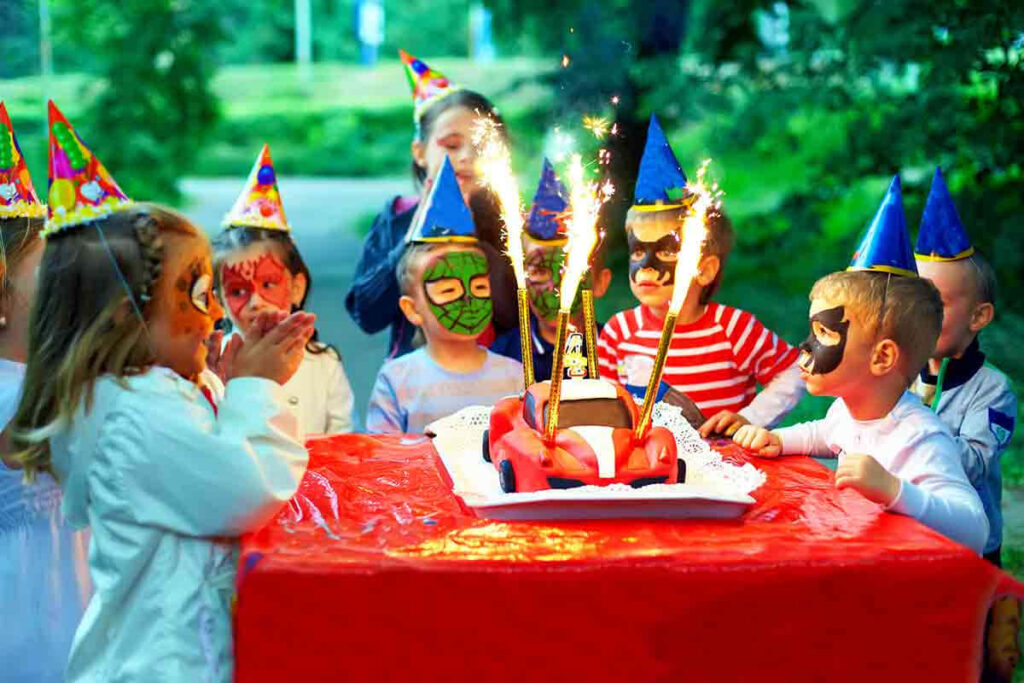 Colorful Birthday Party: Kids with Face Paint & Sparklers Around Cake Wallpaper